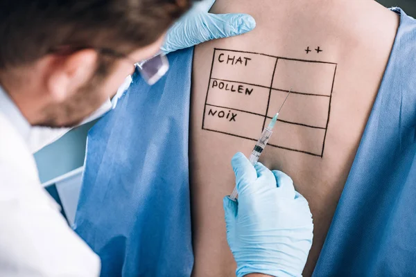 Foco seletivo do alergista segurando pipeta perto do paciente com letras no corpo marcado — Fotografia de Stock