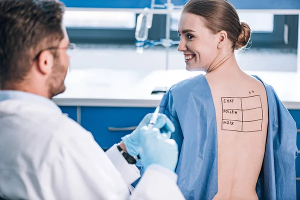 Foco seletivo do paciente feliz com letras nas costas marcadas olhando para o alergista — Fotografia de Stock