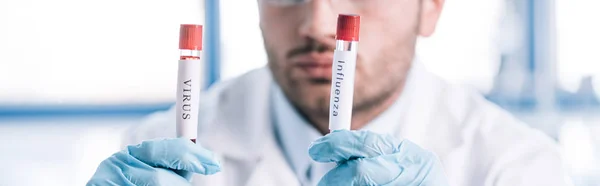 Panoramic shot of bearded immunologist holding test tubes — Stock Photo