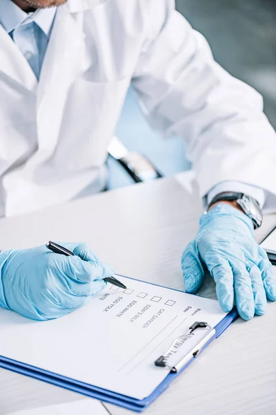 Abgeschnittene Ansicht eines Immunologen, der einen Stift in der Nähe des Klemmbretts hält — Stockfoto