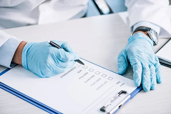 Обрезанный вид иммунолога, держащего ручку возле буфера обмена с контрольным списком — стоковое фото