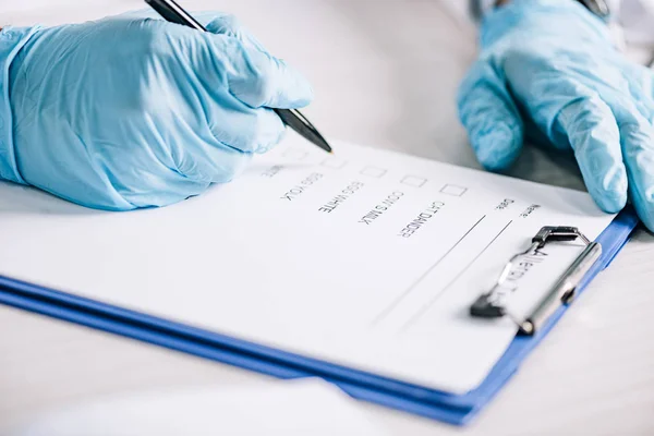 Foyer sélectif de l'immunologiste tenant le stylo près du presse-papiers avec la liste de contrôle — Photo de stock