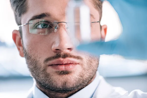 Primer plano del guapo inmunólogo barbudo sosteniendo botella en la clínica - foto de stock