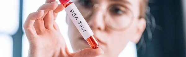 Panoramaaufnahme eines Immunologen in Brille, der auf das Reagenzglas mit psa-Buchstaben blickt — Stockfoto