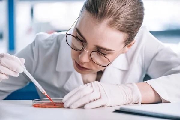 Selective focus of attractive immunologist holding pipette with red liquid — Stock Photo