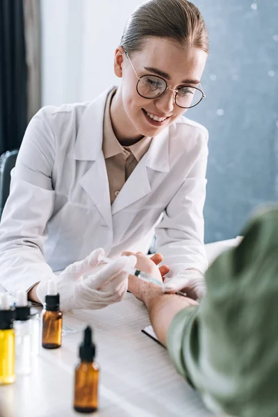 Happy allergist holding syringe near man in clinic — Stock Photo