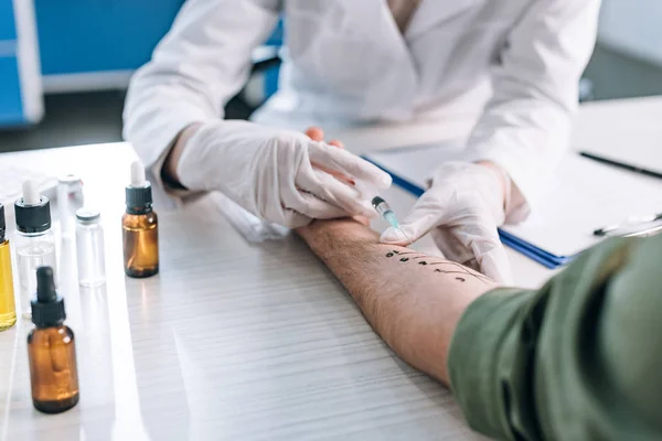 Foco seletivo da seringa de retenção para alergistas perto da mão marcada do doente — Fotografia de Stock