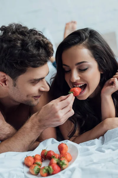 Guapo hombre alimentación atractiva novia con fresa - foto de stock