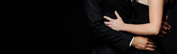 Panoramic shot of man hugging young woman isolated on black — Stock Photo