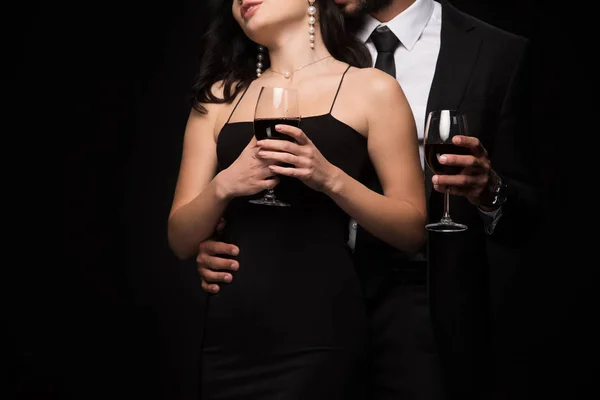 Vista cortada de homem e mulher segurando copos com vinho tinto isolado em preto — Stock Photo