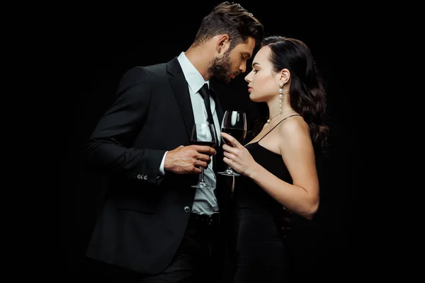 Vue latérale de bel homme et belle femme tenant des lunettes avec du vin rouge isolé sur noir — Photo de stock