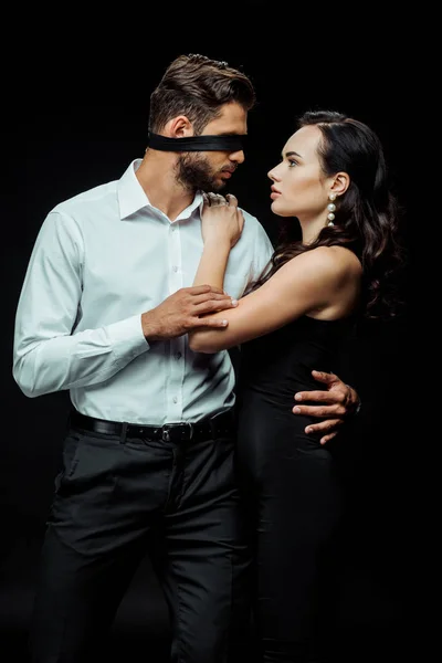 Atractiva mujer mirando con los ojos vendados hombre en negro - foto de stock