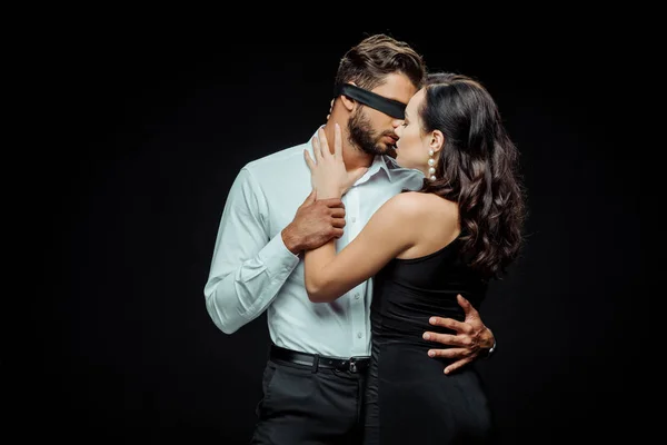 Sexy mujer tocando con los ojos vendados hombre aislado en negro - foto de stock