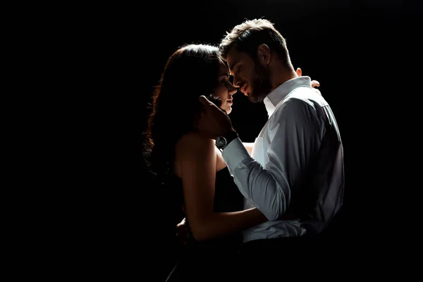 Vue latérale de barbu homme toucher les cheveux de la femme tout en se tenant isolé sur noir — Photo de stock