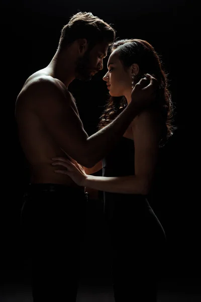 Side view of shirtless man touching attractive woman isolated on black — Stock Photo