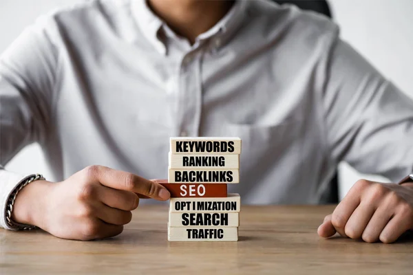 Cropped view of seo manager holding wooden rectangle with seo illustration — Stock Photo