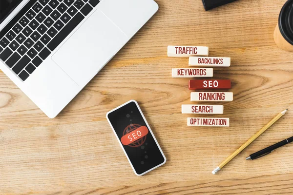 Top view of wooden rectangles with illustration of concept words of seo, smartphone, laptop, pen and pencil — Stock Photo