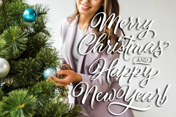 Cropped view of businesswoman decorating christmas tree with merry Christmas and happy new year illustration — Stock Photo