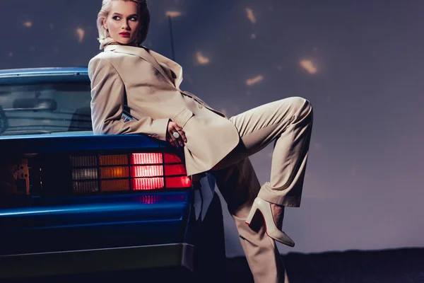 Attractive and stylish woman in suit on retro car looking away — Stock Photo