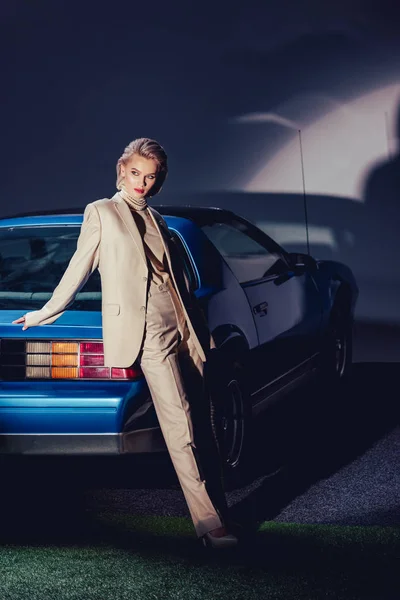 Mujer atractiva y elegante en traje de pie cerca de coche retro - foto de stock