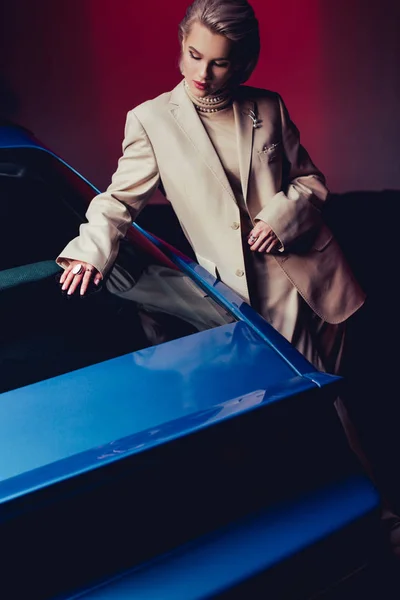 Mujer atractiva y elegante en traje tocando coche retro - foto de stock