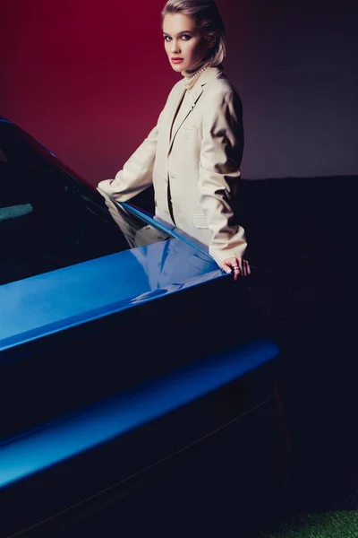 Mujer atractiva y elegante en traje tocando coche retro - foto de stock