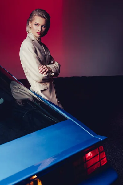 Attractive and stylish woman with crossed arms in suit standing near retro car — Stock Photo