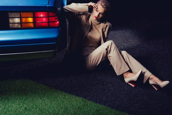 Attraktive und stilvolle Frau im Anzug sitzt in der Nähe von Retro-Auto — Stockfoto