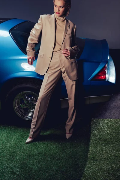 Vista de ángulo alto de la mujer atractiva y elegante en traje de pie cerca de coche retro - foto de stock