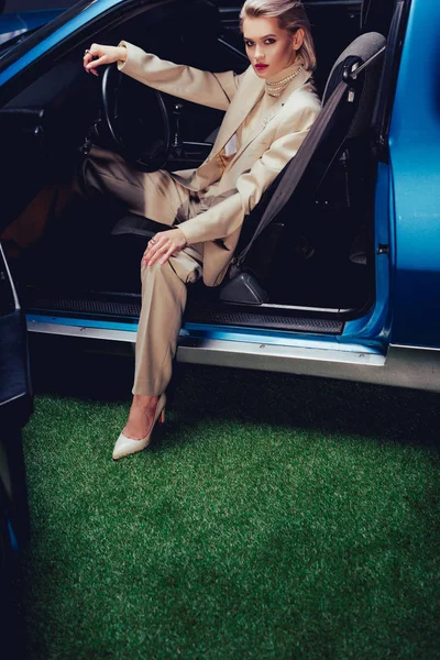 Високий кут зору привабливої і стильної жінки в костюмі сидячи в ретро автомобілі — стокове фото