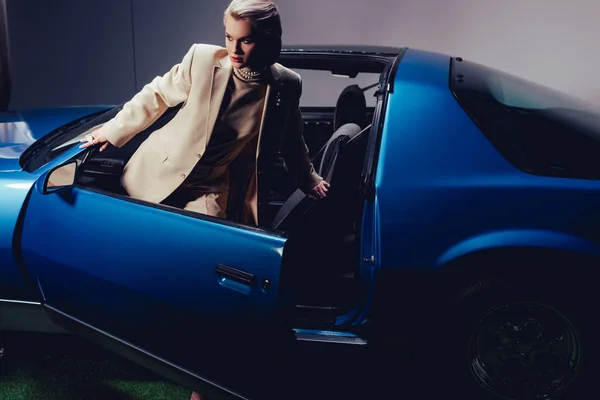 Mujer atractiva y elegante en traje de pie cerca de coche retro - foto de stock