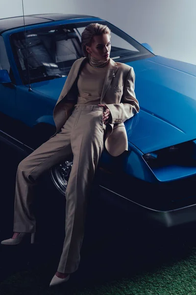 Attrayant et élégant femme en costume assis sur la voiture rétro — Photo de stock