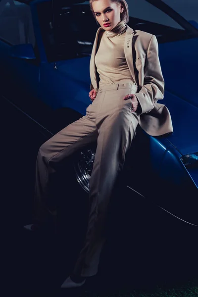 Привлекательная и стильная женщина в костюме сидит на ретро-машине — стоковое фото