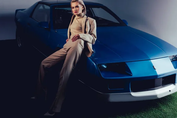 Attractive and stylish woman in suit sitting on retro car — Stock Photo