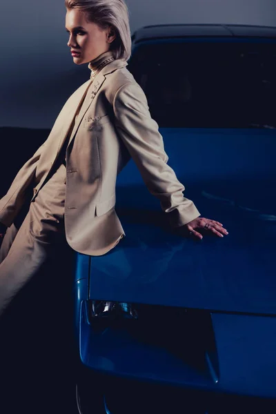 Attractive and stylish woman in suit sitting on retro car — Stock Photo