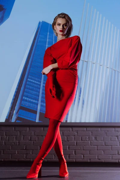 Femme attrayante et élégante en robe rouge sur fond de ville — Photo de stock