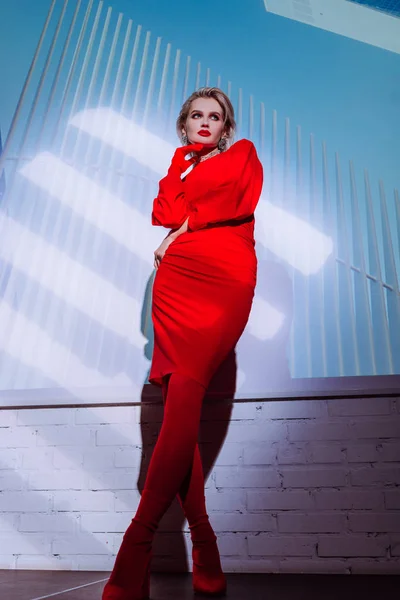 Vista basso angolo di donna attraente ed elegante in abito rosso sullo sfondo della città — Foto stock