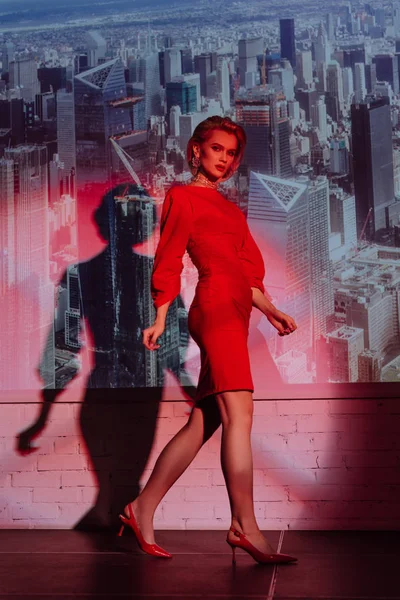 Mujer atractiva y elegante en vestido rojo en el fondo de la ciudad - foto de stock