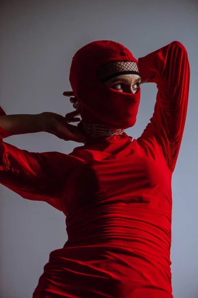 Стильная женщина в красном платье и балаклаве изолированы на сером — стоковое фото