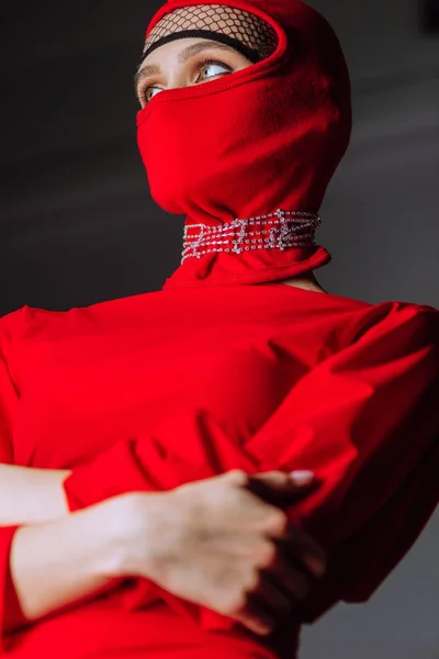 Baixo ângulo vista de mulher elegante em vestido vermelho e balaclava isolado em cinza — Fotografia de Stock