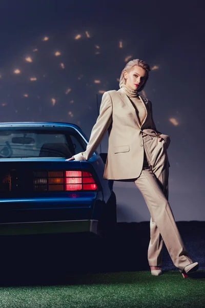 Attractive and stylish woman in suit standing near retro car — Stock Photo