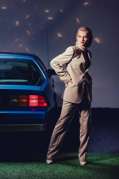 Привлекательная и стильная женщина в костюме стоящая ретро возле автомобиля — стоковое фото