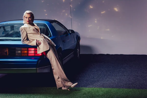 Attrayant et élégant femme en costume couché sur la voiture rétro — Photo de stock