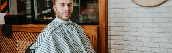 Tiro panorâmico de homem barbudo bonito sentado na barbearia — Fotografia de Stock