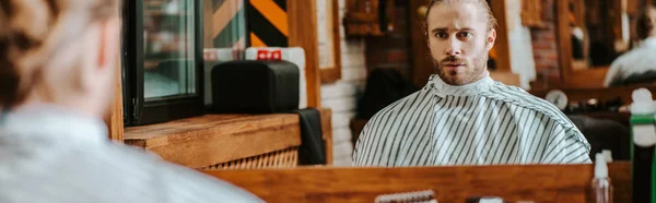 Plano panorámico de hombre barbudo guapo mirando el espejo en la barbería - foto de stock