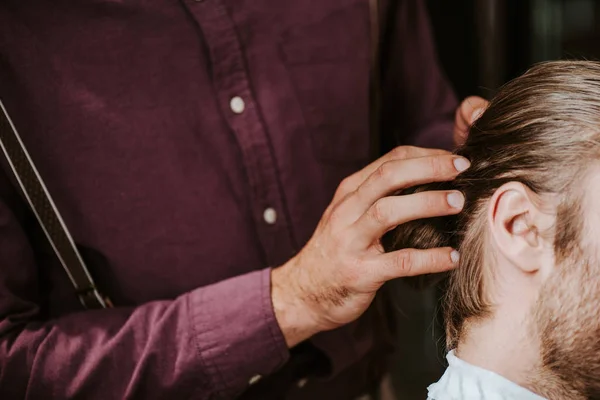 Vista recortada de peluquero tocando el pelo del hombre - foto de stock