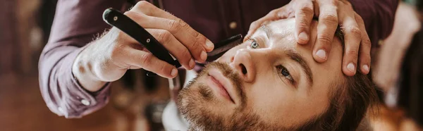 Tiro panorâmico de barbeiro barbeando barba homem — Fotografia de Stock