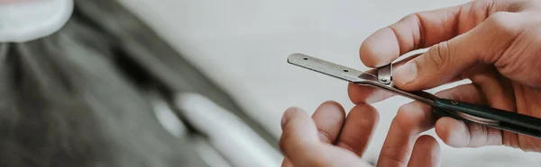 Panoramic shot of barber holding razor in barbershop — Stock Photo