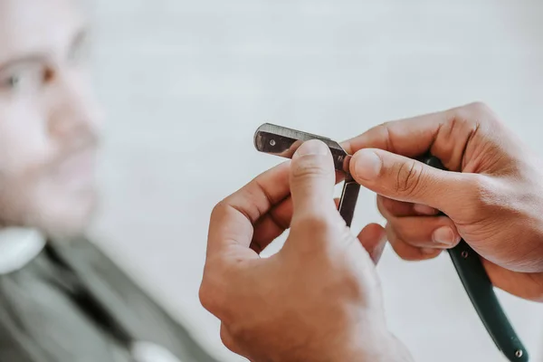 Cropped view of barber holding razor in barbershop — Stock Photo