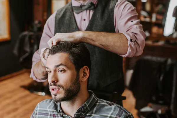 Coiffeur coiffant cheveux sur beau barbu homme — Photo de stock